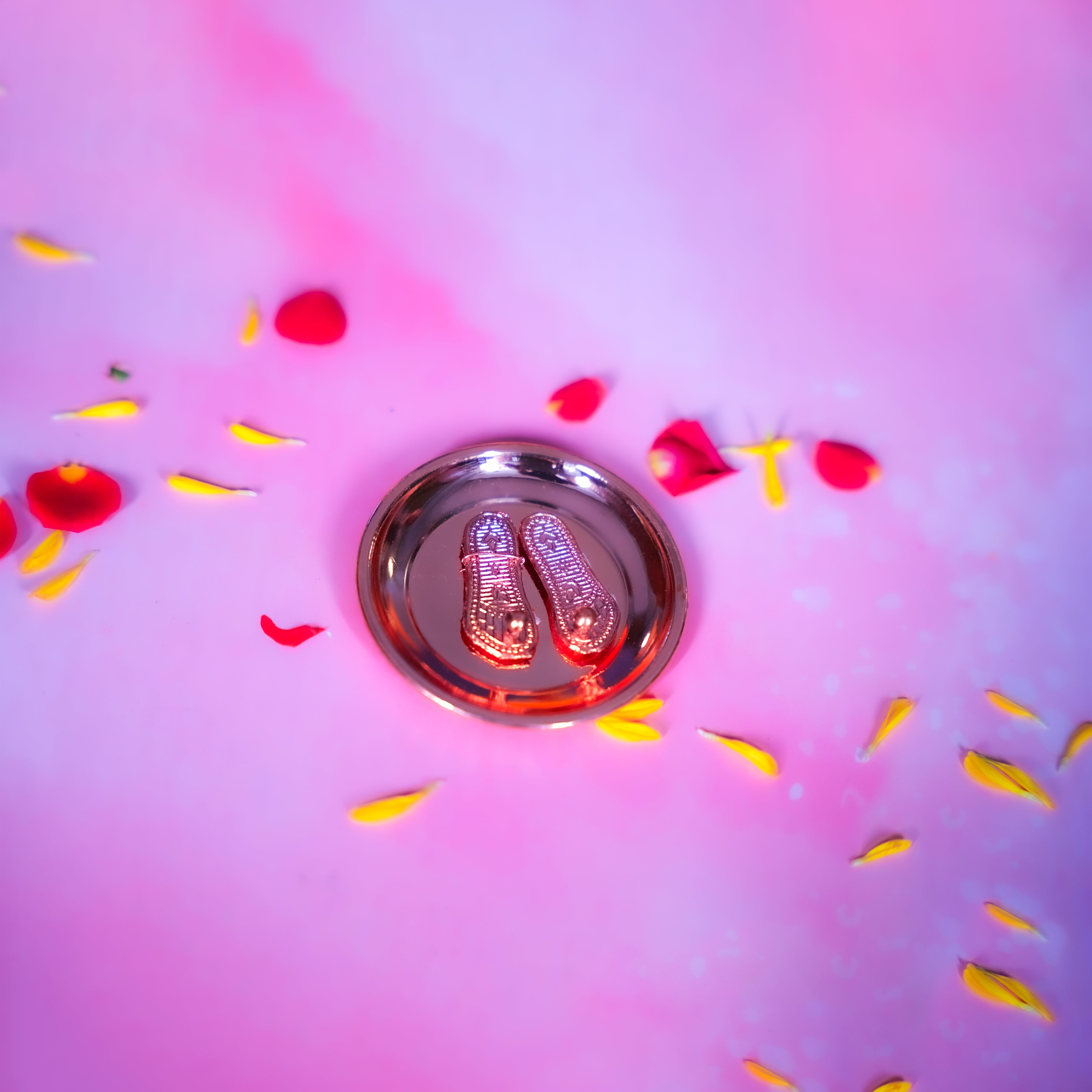 Silver dish with red and yellow petals on a pink background