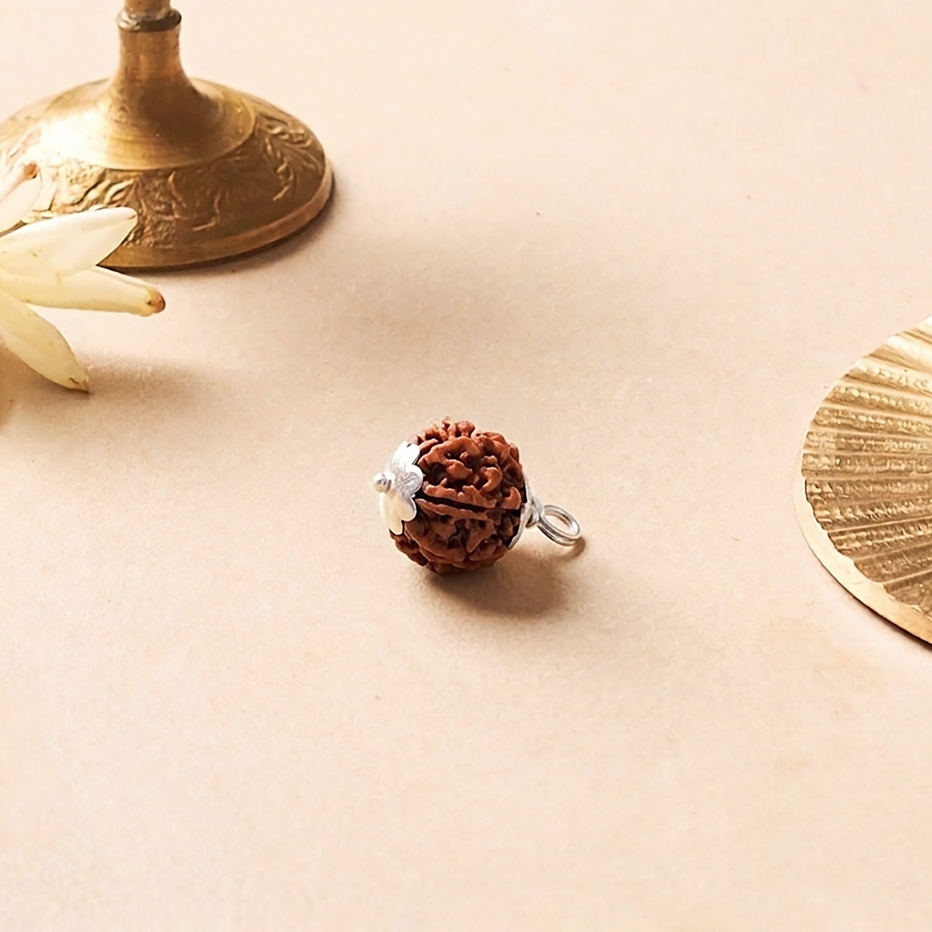 Brown textured ball charm with silver accents on a beige surface