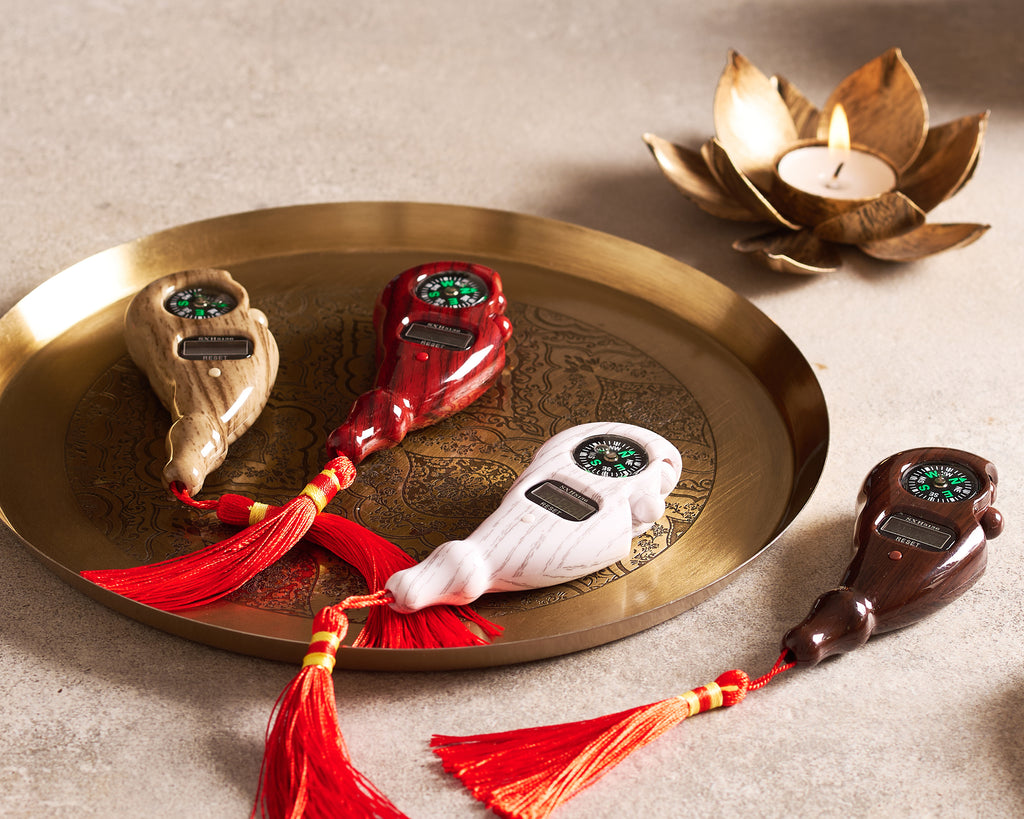 Decorative items with tassels on a brass tray, accompanied by a lit candle.