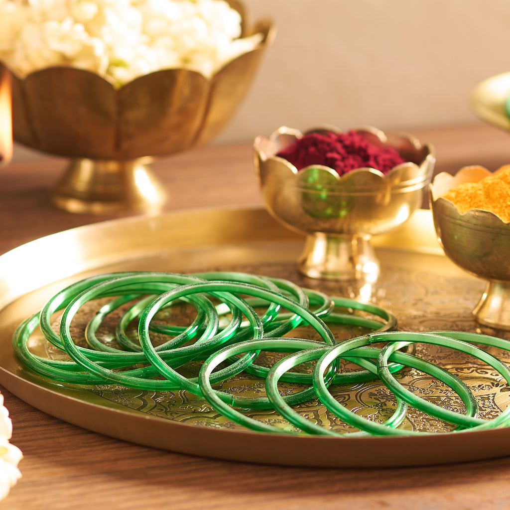 Green bangles on a gold tray with decorative elements in the background