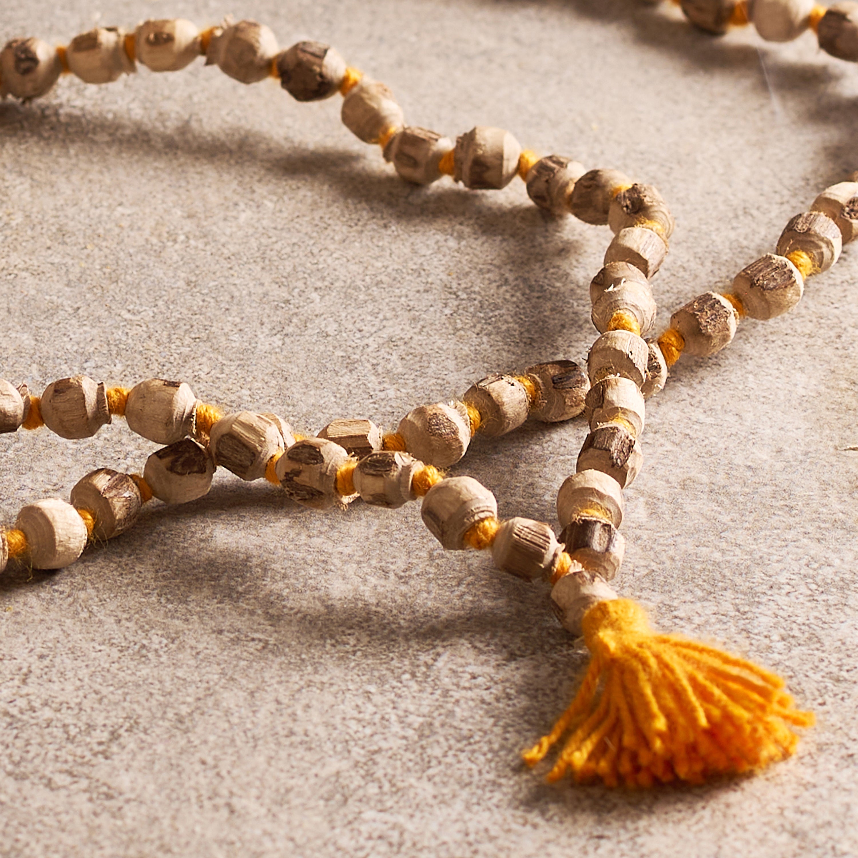 Necklace with wooden beads and a yellow tassel on a textured surface