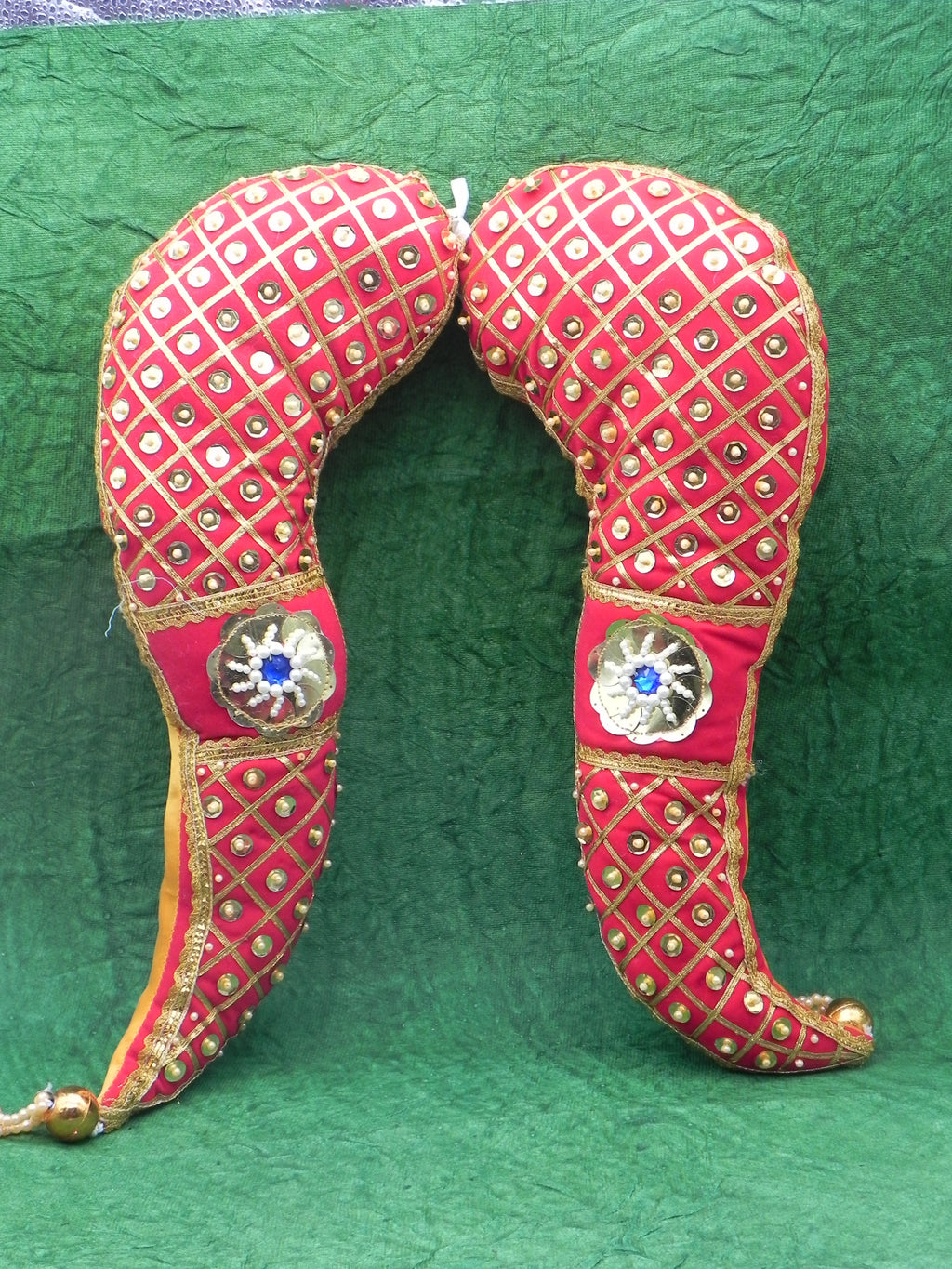 Decorative red and gold headgear with intricate patterns on a green background