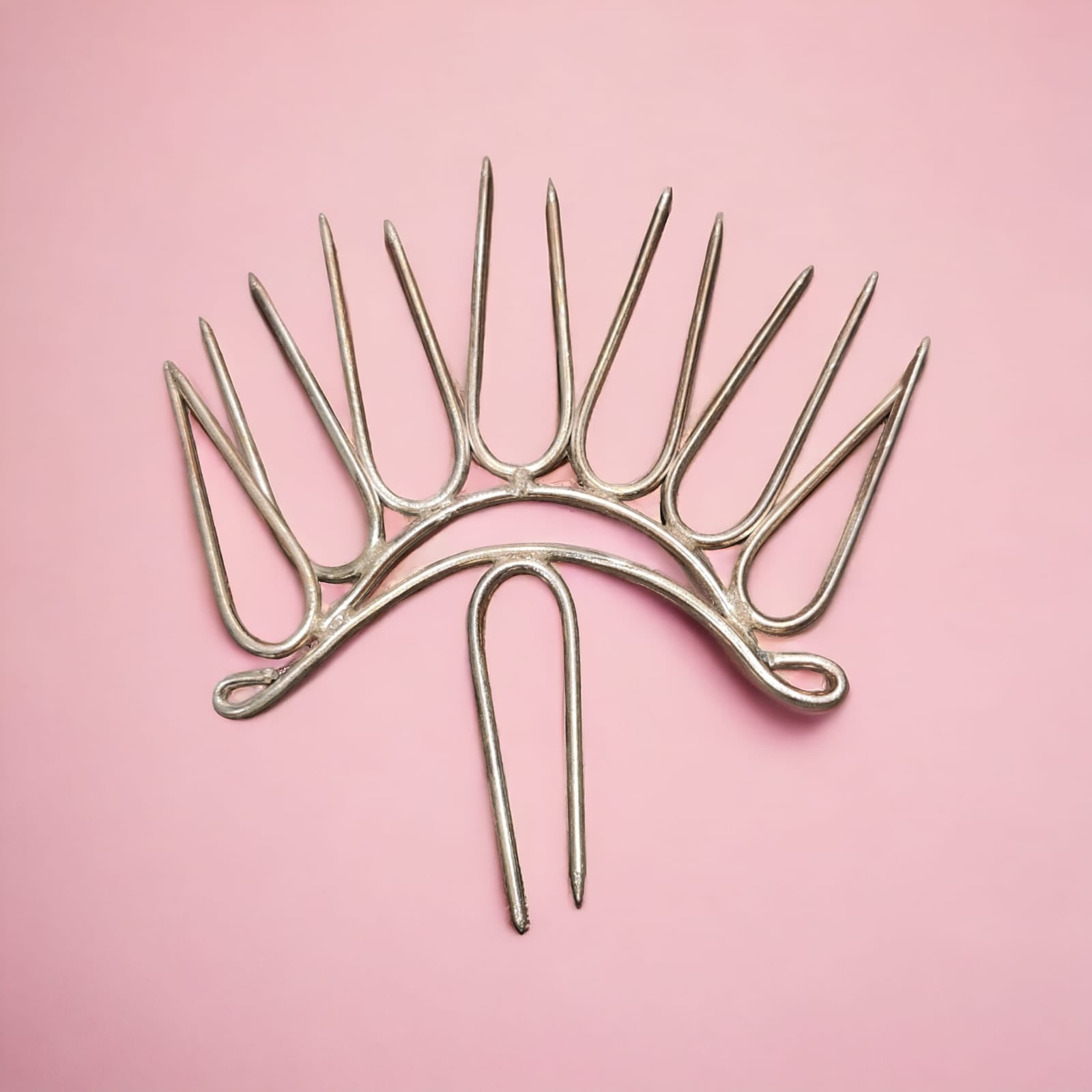 A decorative brass kalash with multiple prongs, placed on a pink background, often used in Hindu rituals and festivals.