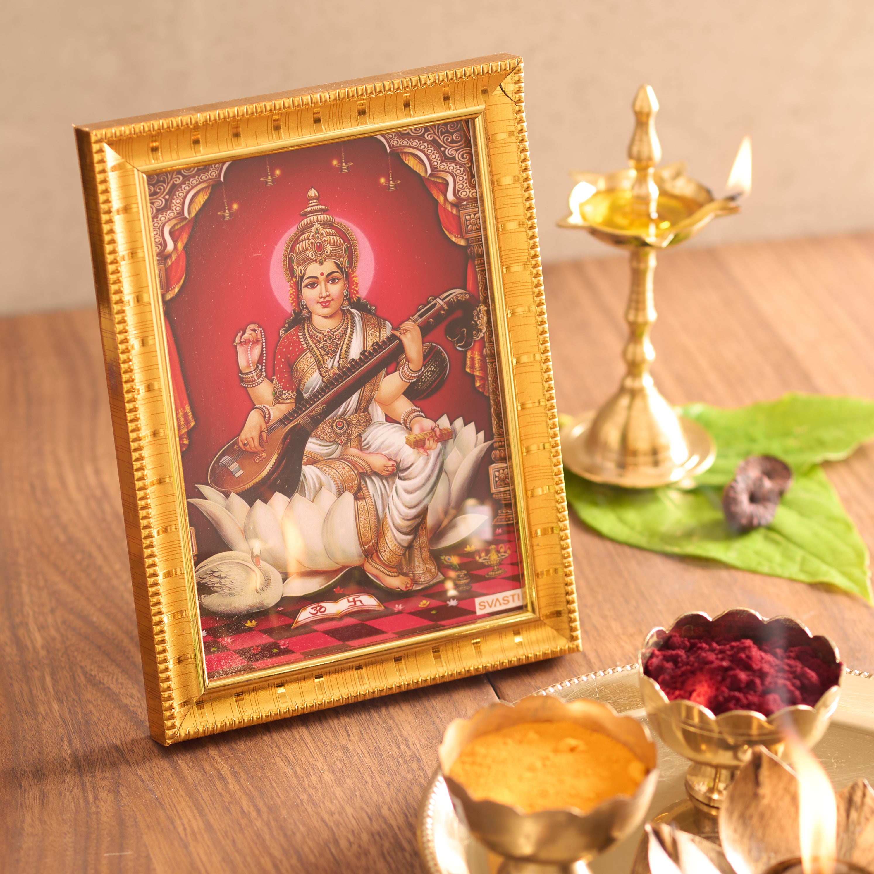 Framed artwork of a deity on a wooden table with decorative items.