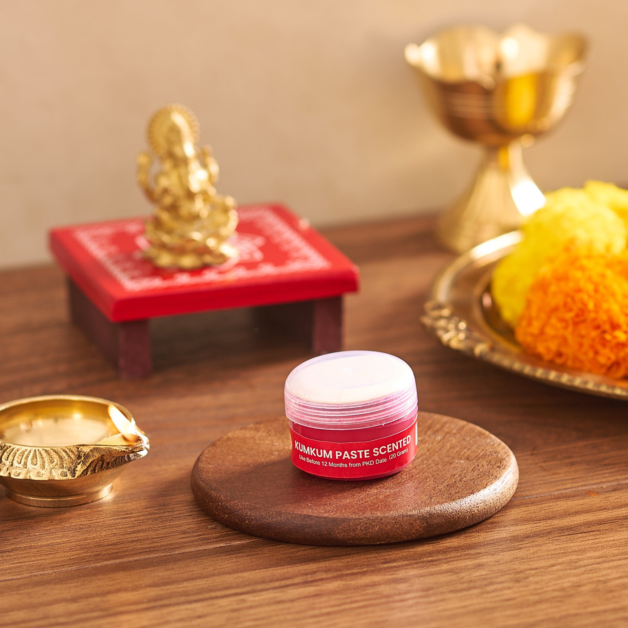 Small container of scented balm on a wooden surface with decorative items in the background
