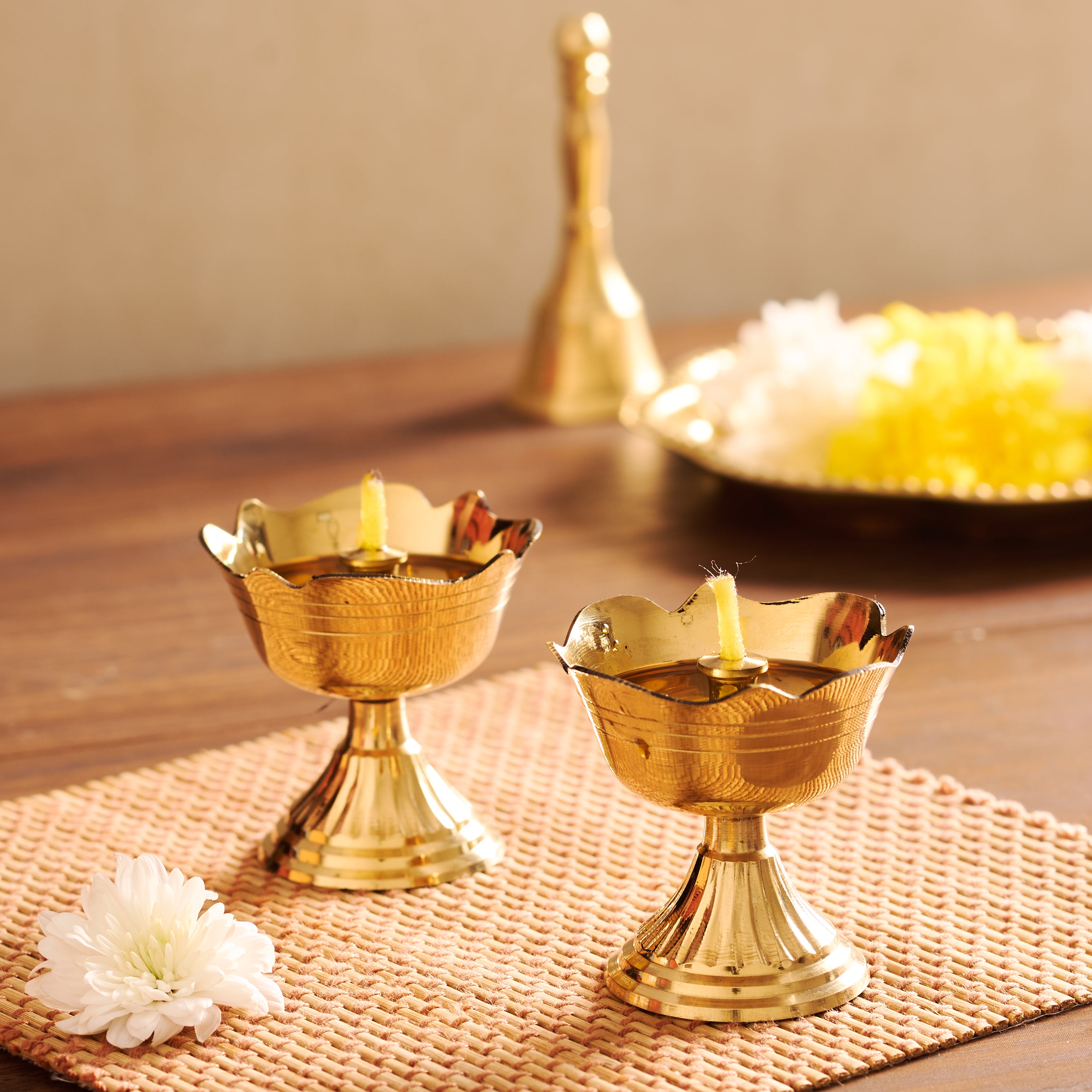 Two gold candle holders with candles on a textured surface.