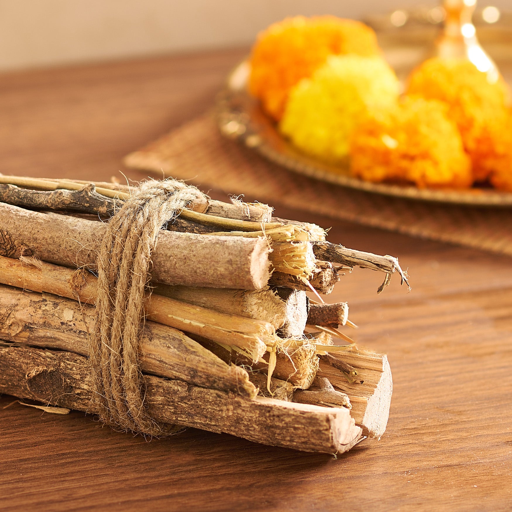 Bunch of sticks tied with twine on a wooden surface with blurred pumpkins in the background