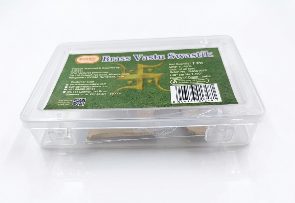 Brass Vastu Swastika tool in a clear plastic box with a green label on a white background