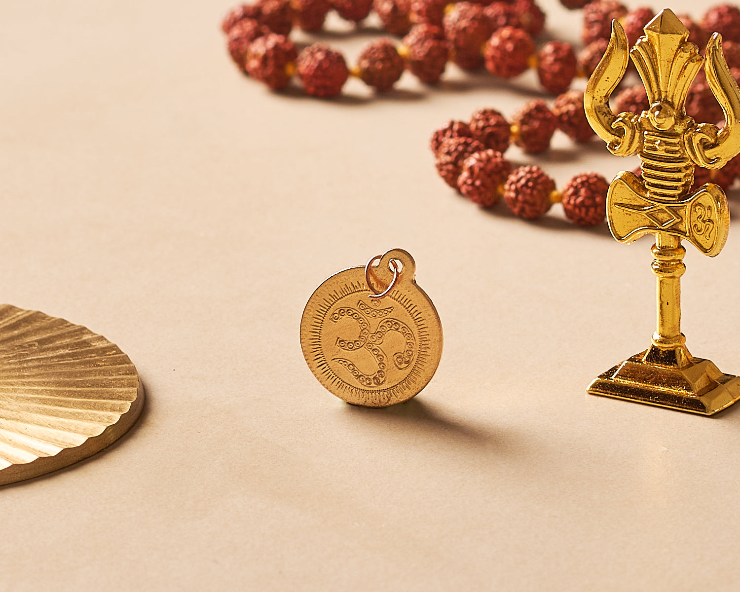 Gold religious symbols including a pendant, statue, and rosary on a beige background