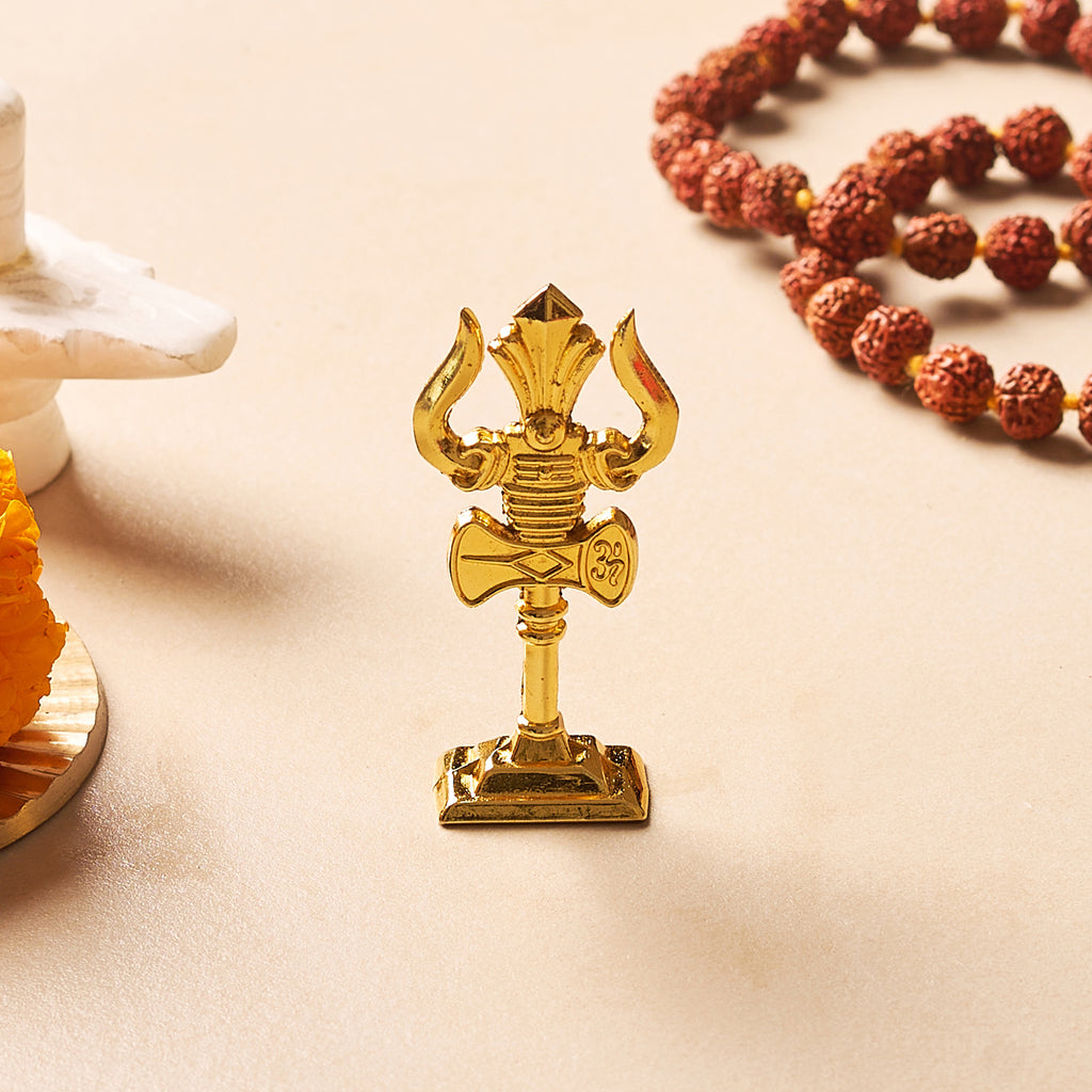 Gold-colored religious symbol on a beige surface with a rosary in the background