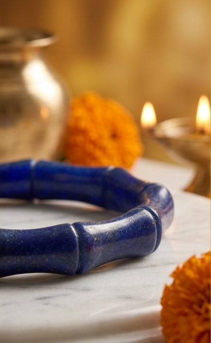 Triptych of a blue bracelet on a marble surface with decorative elements and candles.