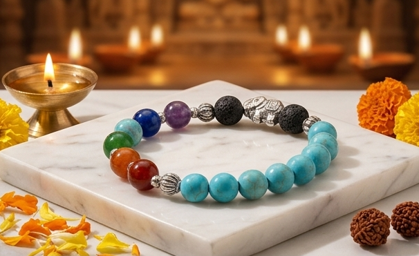 Colorful beaded bracelet on a pedestal with decorative items including a kalash and diya, set against a warm, candlelit background.