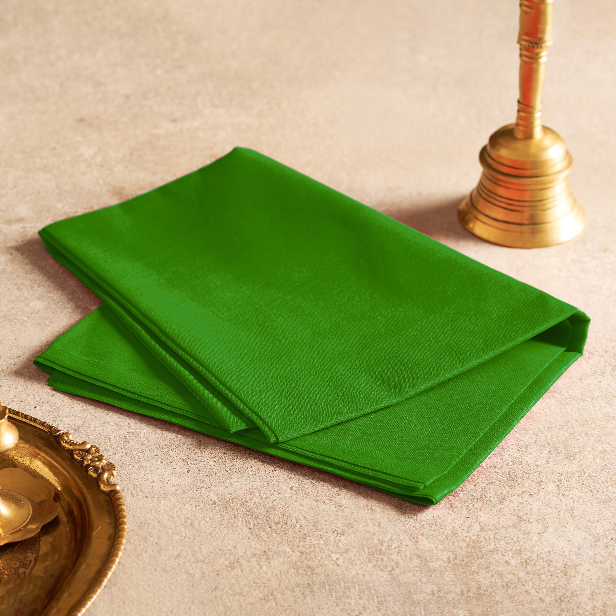 Green napkin on a beige surface with gold decorative items