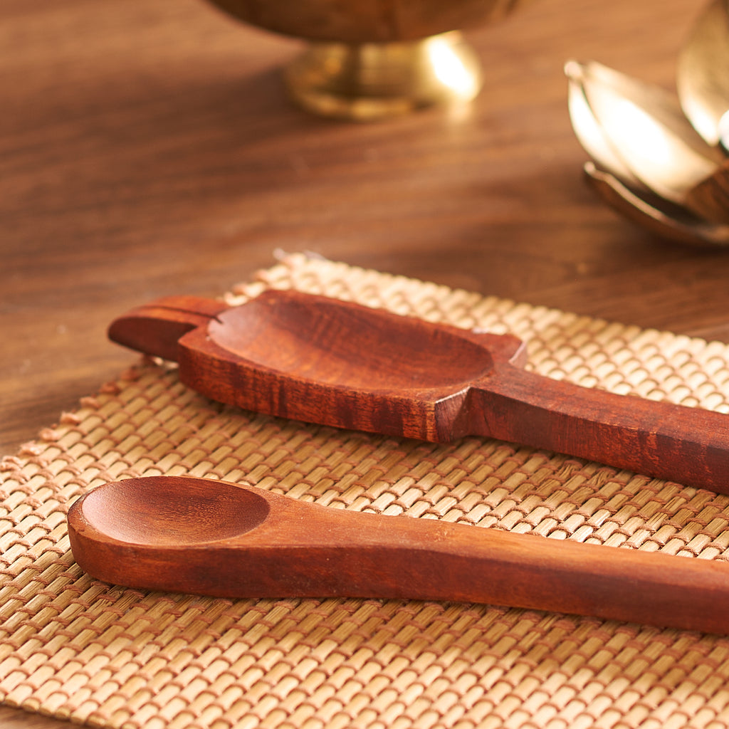 Two wooden spoons on a woven mat with a blurred background