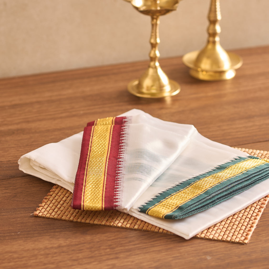 White napkin with colorful stripes on a wooden table with gold candle holders.