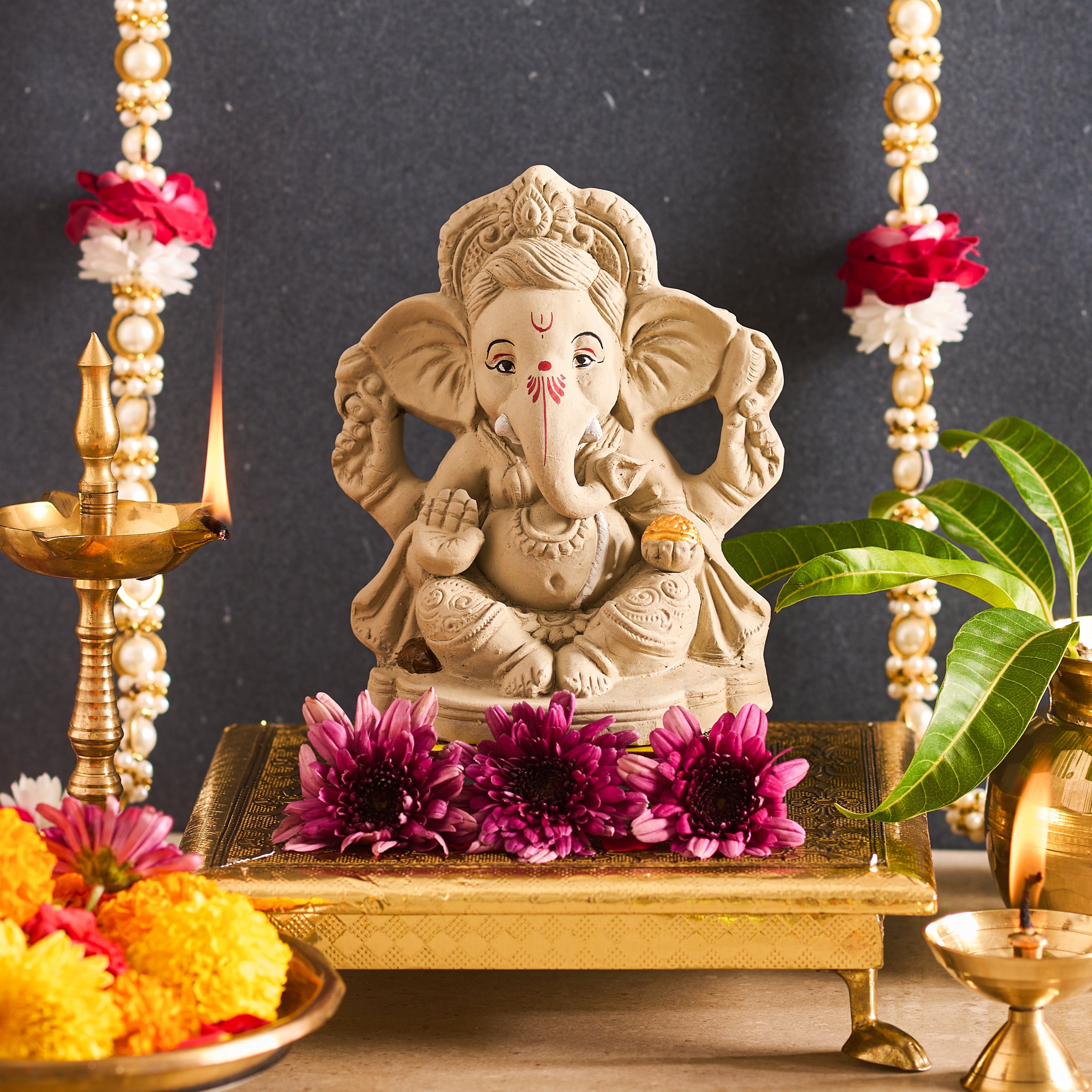 Statue of a deity with flowers and candles on a dark background