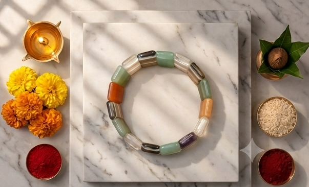 Collage of a colorful bracelet on a marble surface with decorative elements and candles.
