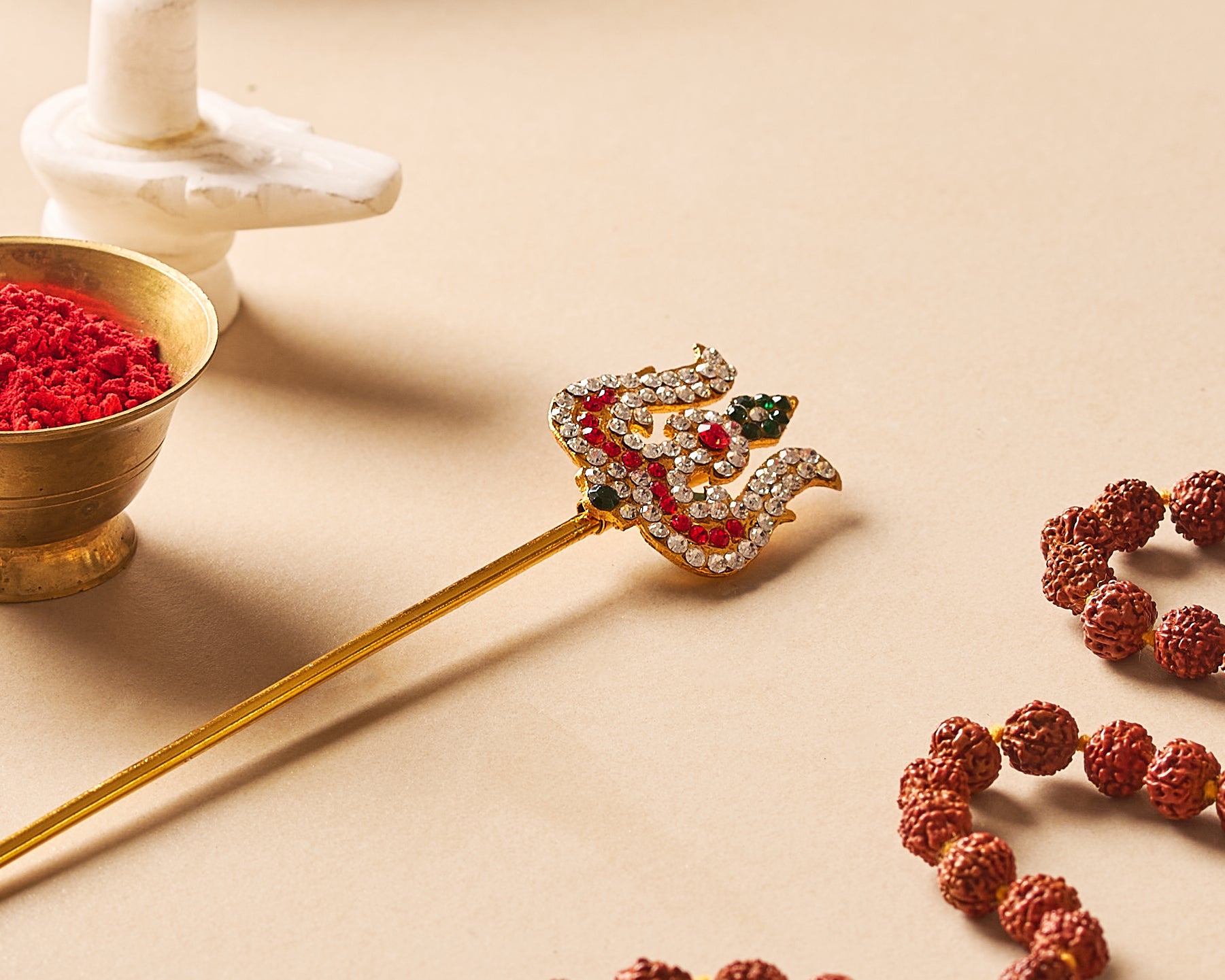 Clear front-facing shot of the gold-plated stone trishul centered against a clean white background, showcasing the full vertical profile from the stem base to the stone-studded top.
