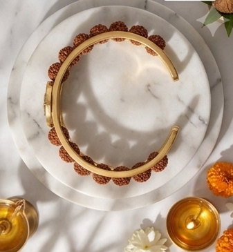 Gold bracelet with maroon stones on a decorative table with candles and flowers