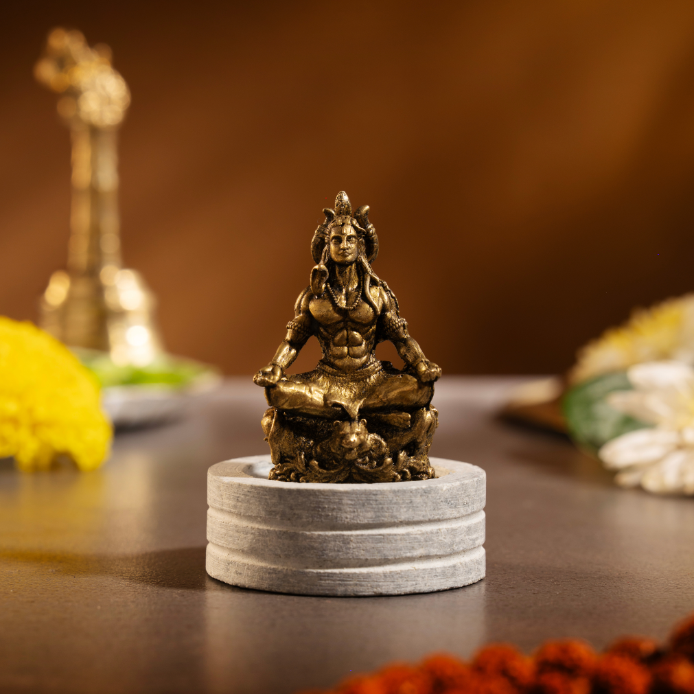Front view of a small antique-finish brass Shiva idol in a seated meditation posture.