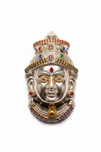A silver-toned Hindu deity face mask with gold, red, and blue gemstone accents, isolated on a white background.