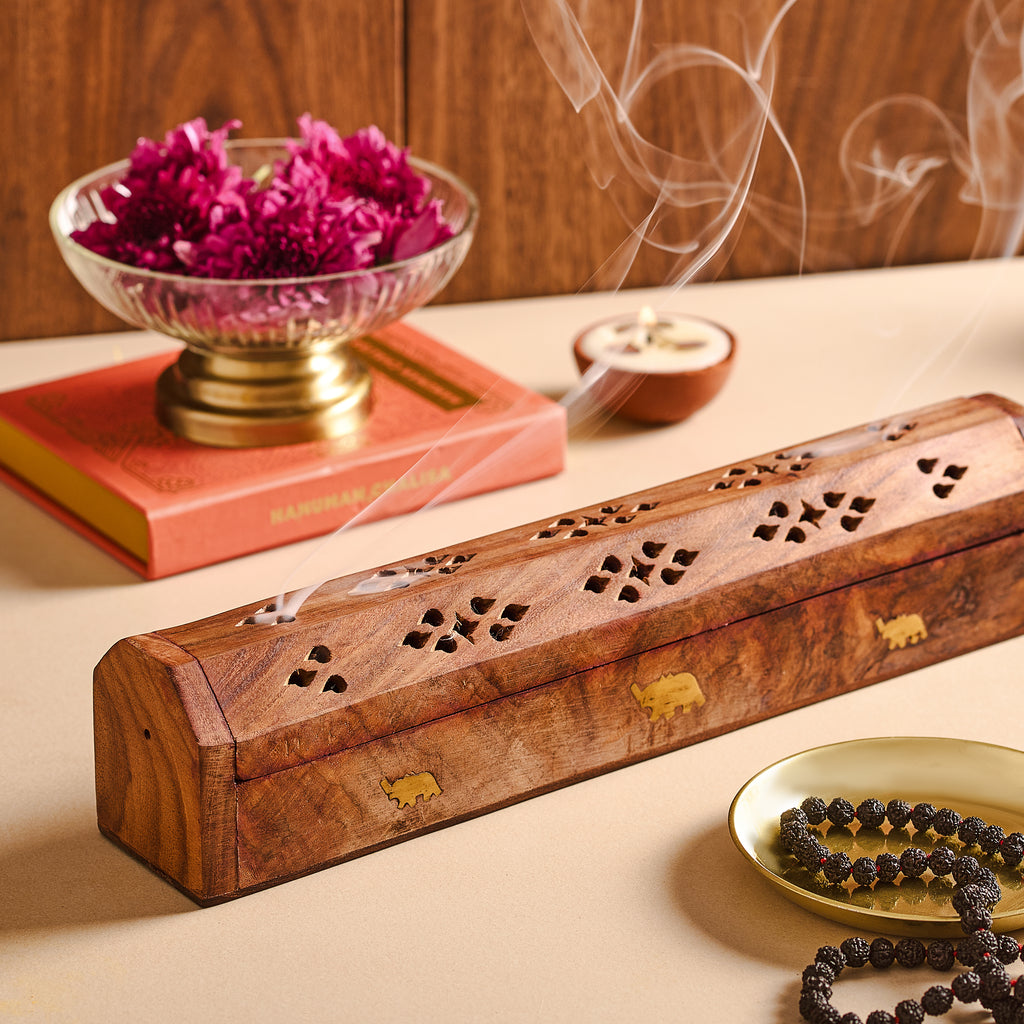 Wooden incense burner with purple flowers and a candle on a wooden surface