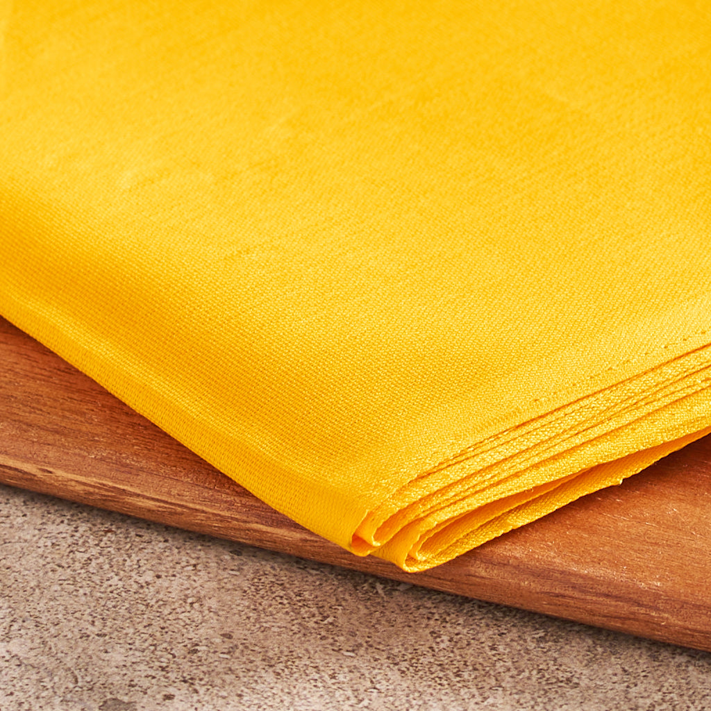 A close-up macro view focusing on the surface texture and fine intersecting cotton threads of the yellow cloth to showcase fabric density and dye consistency.