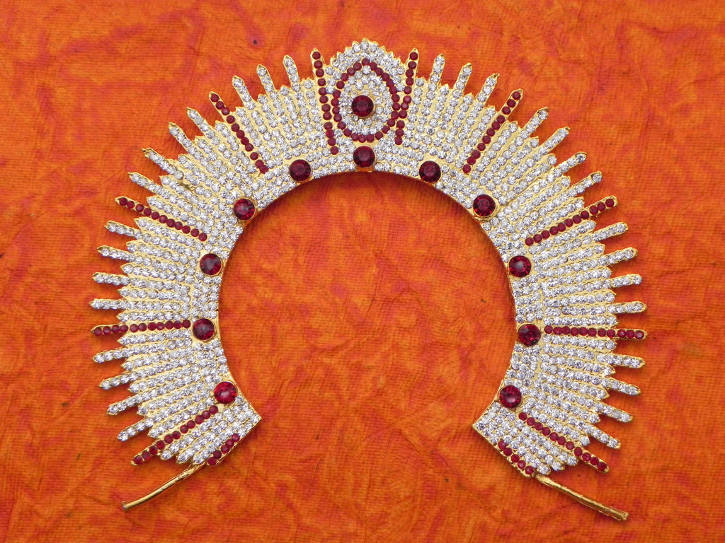 An arch-shaped decorative item with multicolor stones and a metallic back, displayed against an orange textured background.